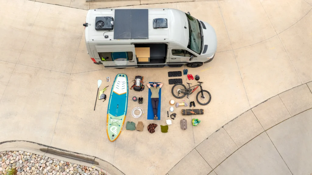 aerial view of a man laying down on yoga mat with gear and a camper van